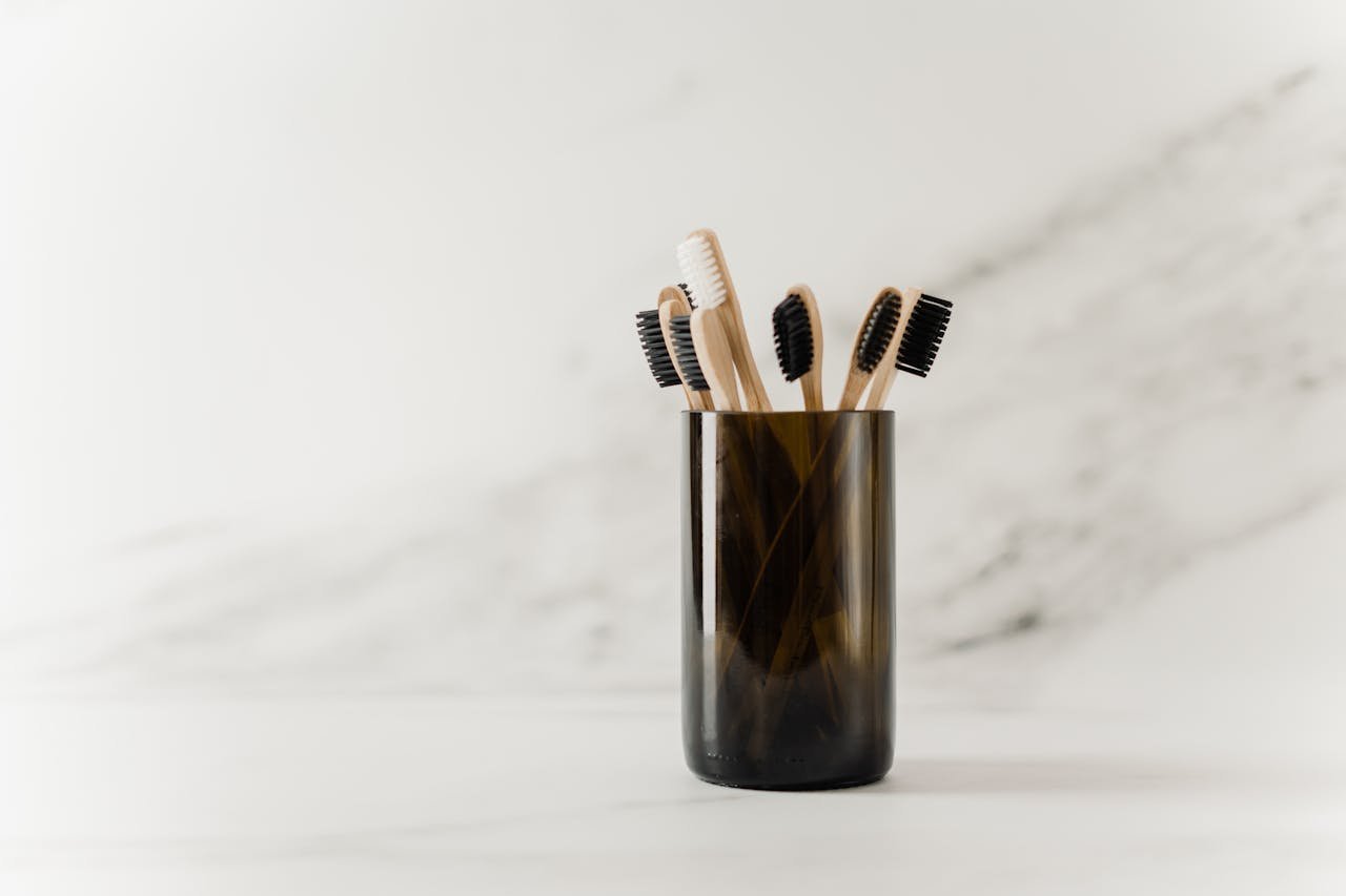 Set of eco-friendly bamboo toothbrushes in a glass holder, showcasing a minimalist design.